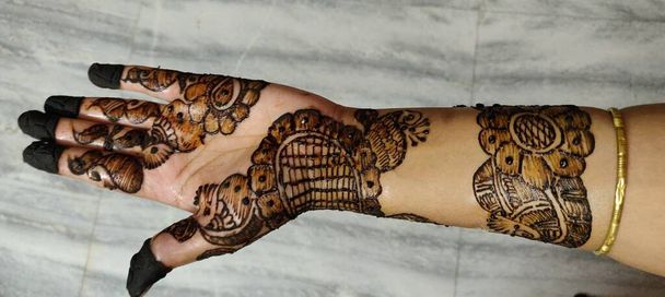 Hands of Indian bride girl with black henna tattoos on rough background - Photo, Image