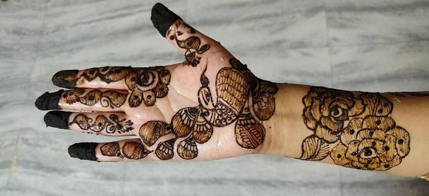 Vrouw Hand met zwarte mehndi tatoeage. Hand van Indiase bruid meisje met zwarte henna tatoeages. - Foto, afbeelding