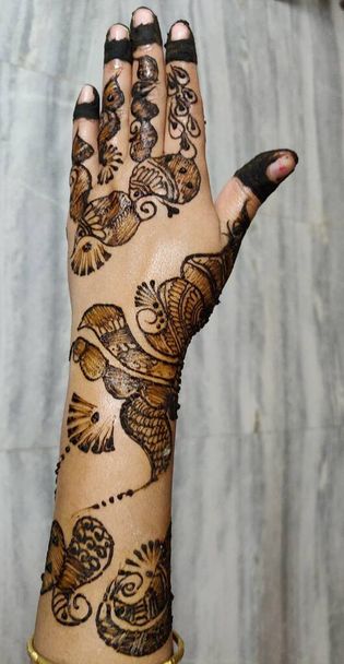Hands of Indian bride girl with black henna tattoos on grey background. - Photo, Image