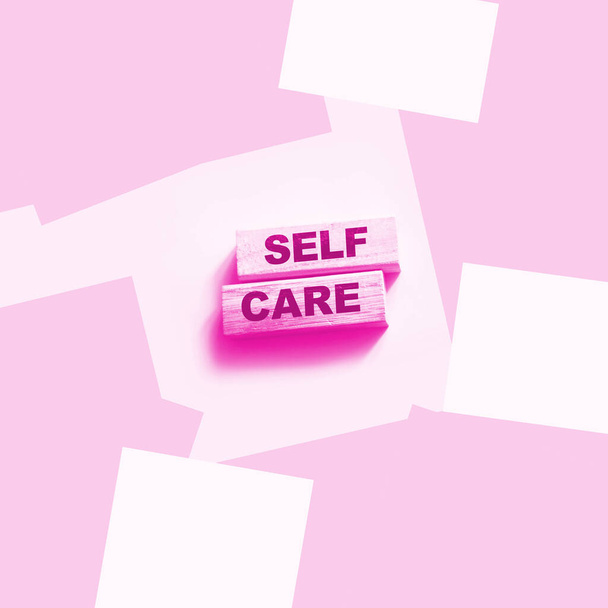 Palavras de autocuidado impressas em blocos de madeira, conceito de autotratamento, fundo rosa - Foto, Imagem
