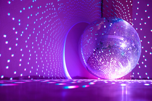 Disco bal reflecteert paars licht. Vakantie concept. Kopieerruimte. - Foto, afbeelding