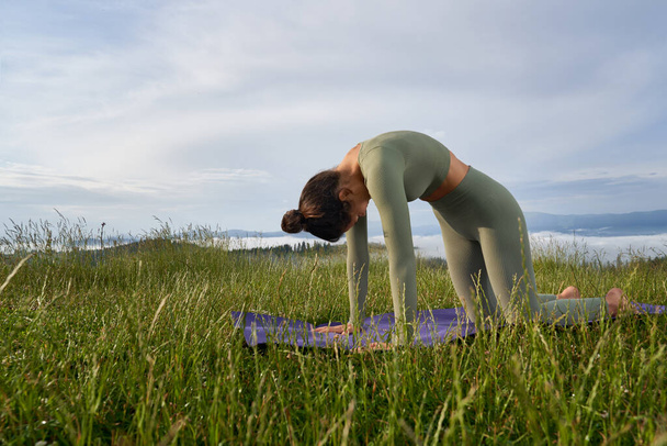 Woman in sport clothes doing yoga exercises outdoors - Fotoğraf, Görsel