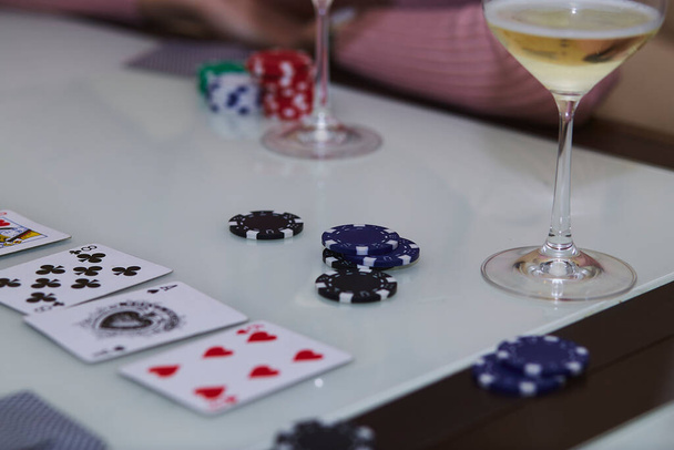 Poker gra z żetonami, karty, kieliszki szampana na stole z odbiciem. Ciesząc się chwilą z przyjaciółmi, detox cyfrowy. Fotografia ze stylem życia. Szczera chwila. Skupienie selektywne - Zdjęcie, obraz