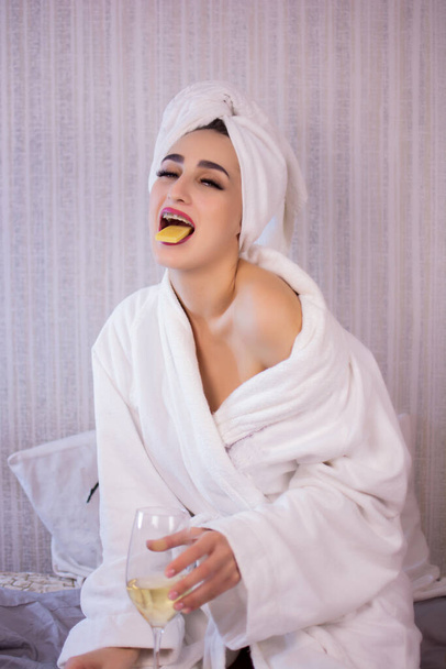 Beautiful girl with a towel on her head drinks wine. - Foto, immagini
