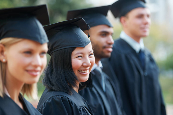 Várom a jövőjüket. Fiatal főiskolai diplomások tartják diplomájukat, miközben sorban állnak és mosolyognak.. - Fotó, kép