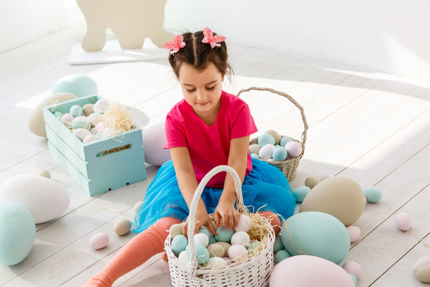 Je me prépare pour Pâques. Belle petite fille tenant un œuf de Pâques et souriant avec décoration en arrière-plan - Photo, image