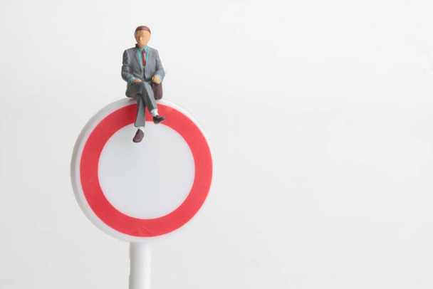 miniature figurine of a business man sitting on a denied access sign - Φωτογραφία, εικόνα
