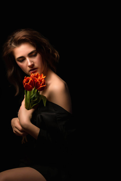 krásné červené tulipány květiny v ruce na černém pozadí. Gratulujeme k dámskému a Valentýnskému dnu.Mezinárodní den žen. Valentýn. - Fotografie, Obrázek