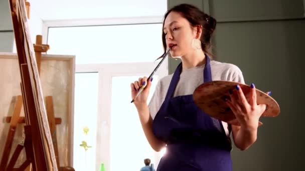 Atelier d'art - jeune femme en tablier bleu dessin d'une peinture - Séquence, vidéo
