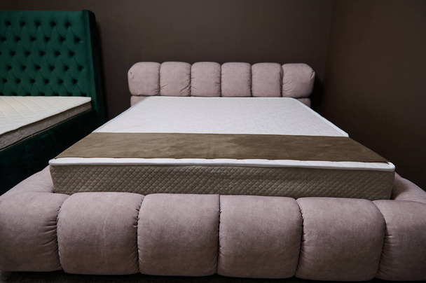 Bellissimo letto morbido rosa elegante con un materasso rigido ortopedico esposto nello showroom di un negozio di mobili, in vendita - Foto, immagini