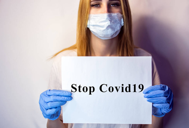 A girl in a mask on her face holds a no Covid19 sign in her hands. The tablet in the hands of a girl on a white background. Blonde with a white table in her hands. No covid 19. Nurse with a placard in his hands. - Fotoğraf, Görsel
