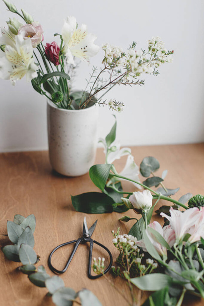 Bouquet elegante em vaso de cerâmica no peitoril da janela de madeira. Lindas flores frescas e tesouras em fundo de madeira, arranjo floral. Bouquet moderno Primavera - Foto, Imagem