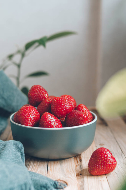 Fresh ripe strawberry on a plate on green leaves background. Big red berries for a healthy breakfast in the village. Food photo in rustic style - Fotografie, Obrázek