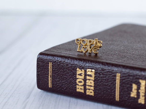 God is love quote message written with gold letters on a closed Holy Bible Book isolated on a light grey background. A closeup. The Christian biblical concept of grace and mercy of God Jesus Christ. - Foto, afbeelding