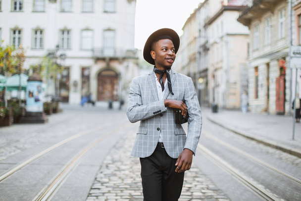 Hombre africano en traje elegante y sombrero caminando por la calle de la ciudad - Foto, Imagen