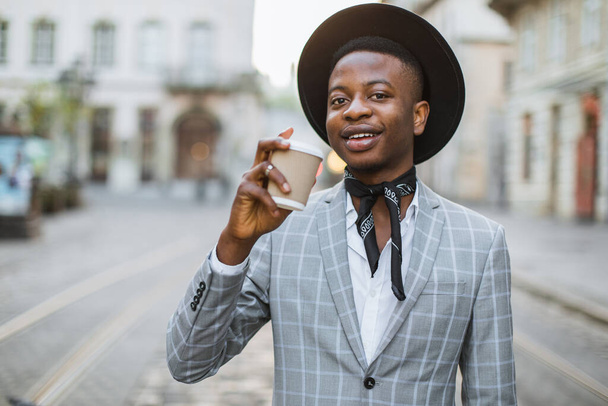 African man in stylish suit drinking coffee on city street - Zdjęcie, obraz