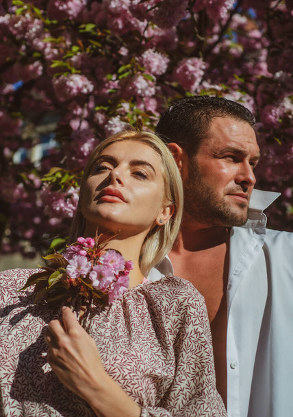 Sensual woman and man in pink flowers in summer blossom park. - Fotografie, Obrázek