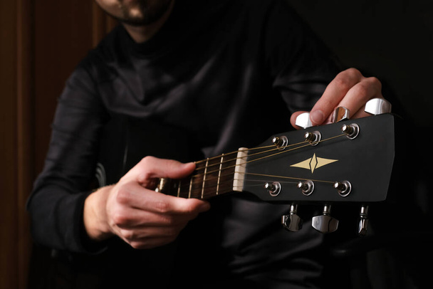 male musician tuning the strings on the guitar - Foto, Bild