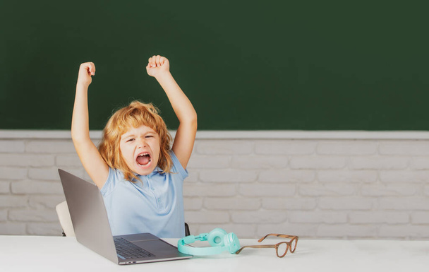 Elementary school kid angry and sad. Pupil screaming shouting in classroom. Bad school boy. - Photo, Image