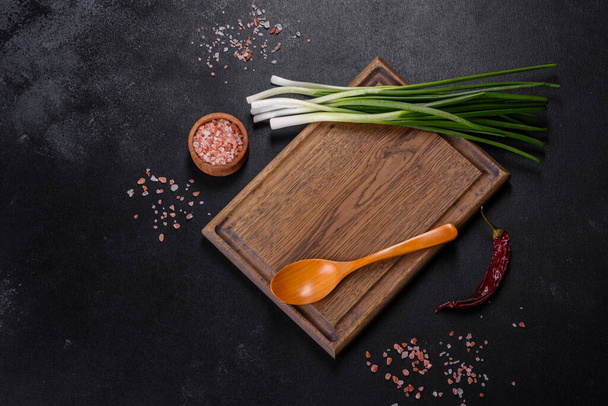 Cut Green onions chives on a cutting board. Dark wooden background - Photo, Image