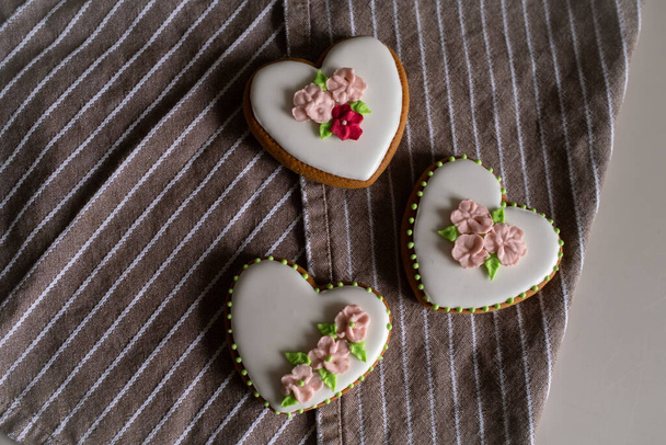 White gingerbread cookies with icing and flower decoration on a striped towel. Background for International Womens Day or Valentines Day. - Foto, Imagen