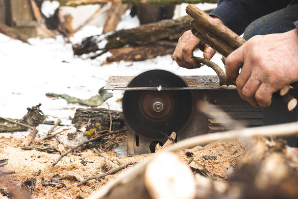 Uomo taglio del legno con sega circolare fissa all'aperto in inverno per accendere primo piano - Foto, immagini