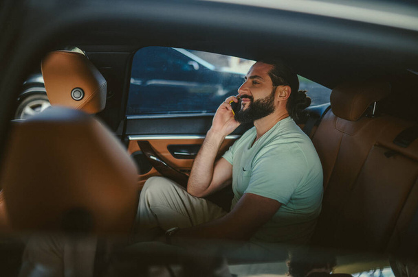 Egy jóképű fiatalember beszél telefonon egy autóban. - Fotó, kép