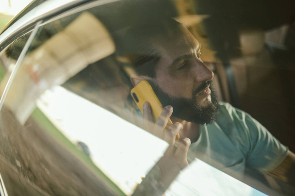 A handsome young man talking on the phone in a car - Fotó, kép