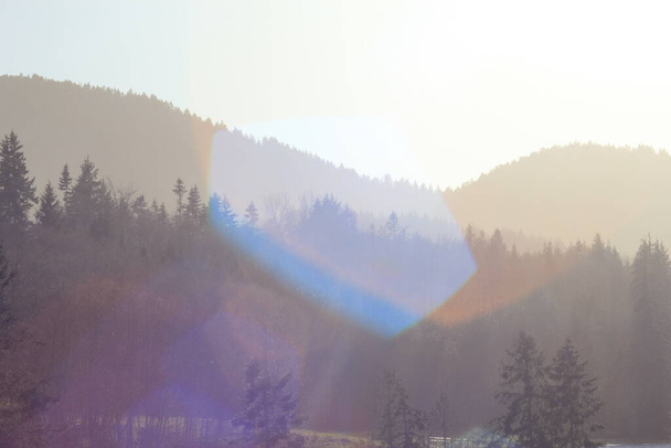 Mountains and pines intersect in the evening, gradation of sunlight and mountains with lens flares. - Photo, Image