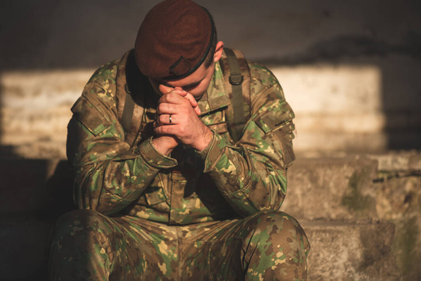 Στρατιώτης ντυμένος με στολή καμουφλάζ προσεύχεται στο Θεό - Φωτογραφία, εικόνα