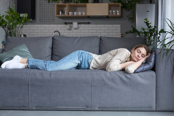 Уставшая блондинка средних лет спит на диване после работы - Фото, изображение