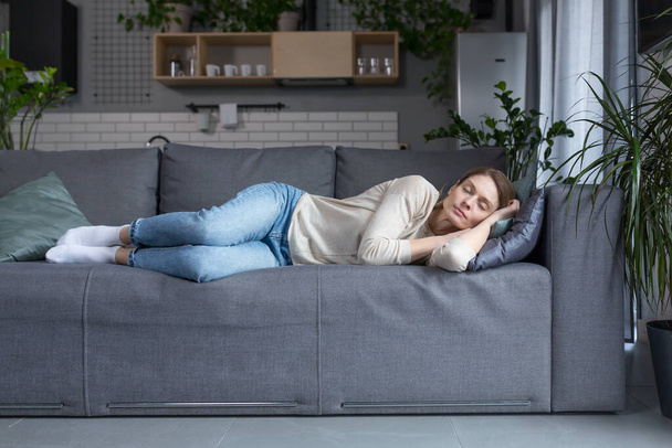 Tired middle aged blonde woman sleeping on sofa after work - Photo, image