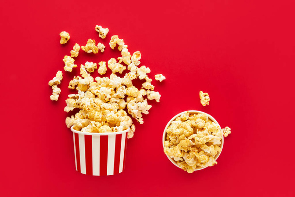 Due scatola rotonda a strisce con popcorn su uno sfondo rosso brillante. Vista dall'alto, copia spazio - Foto, immagini