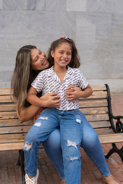 Hispanic Mother and daughter playing on a bench - Photo, Image