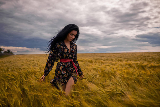 Attractive girl walks through wheat field, touching the spikelets - Photo, image