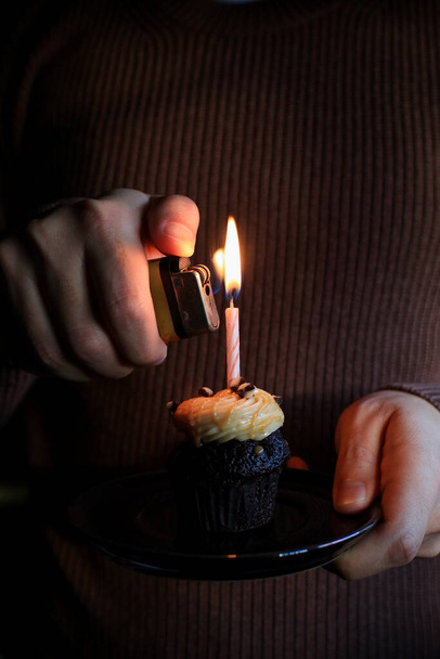 Chocolate Birthday cupcake with a single candle light on dark background. - Foto, imagen