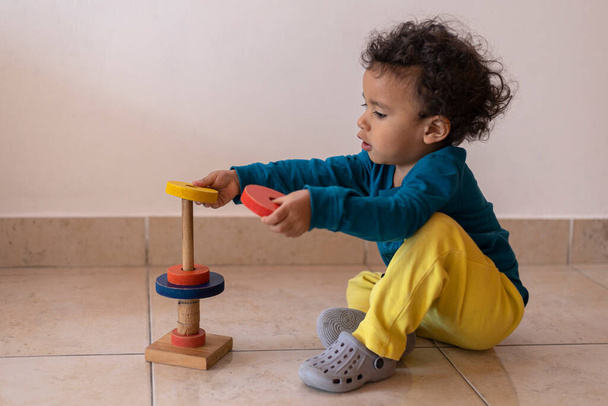 Chlapec z Latinské Ameriky (2) naskládal své dřevěné obruče na podlahu svého domu. Dětský koncept - Fotografie, Obrázek