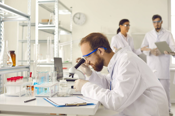 Professional male scientist looking through microscope in research laboratory - Foto, immagini