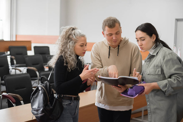 Two girls and a guy are talking in sign language. Three deaf students chatting in a university classroom. - Fotografie, Obrázek