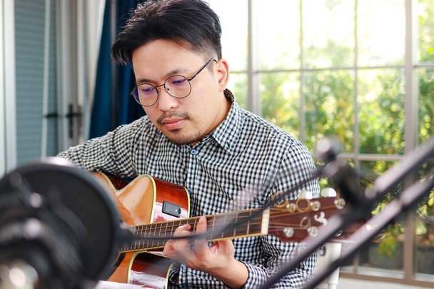 Asijský hudebník umělec Sedět a hrát na kytaru ve studiu. Hudební koncept. online hudební lekce - Fotografie, Obrázek