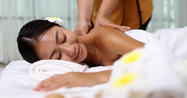 Young Asian woman receiving an oil massage on her back at spa salon by professional masseuse, Spa treatment and aroma oil massage concept - Photo, image