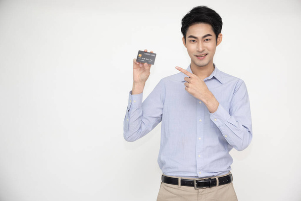 Young Asian man smiling, showing, presenting credit card for making payment or paying online business, Pay a merchant or as a cash advance for goods, Cardholder or A person who owns a card - Foto, immagini