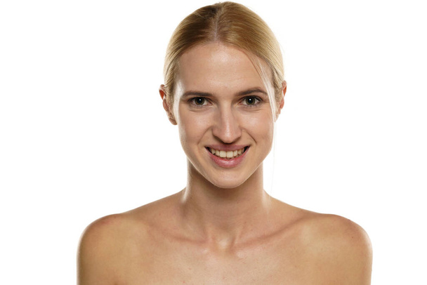 Jovem loira sorrindo mulher sem maquiagem, e com cabelo amarrado em um fundo branco - Foto, Imagem