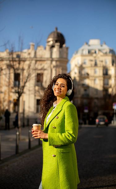 Pretty young woman listening music with headphones on the street - Foto, immagini