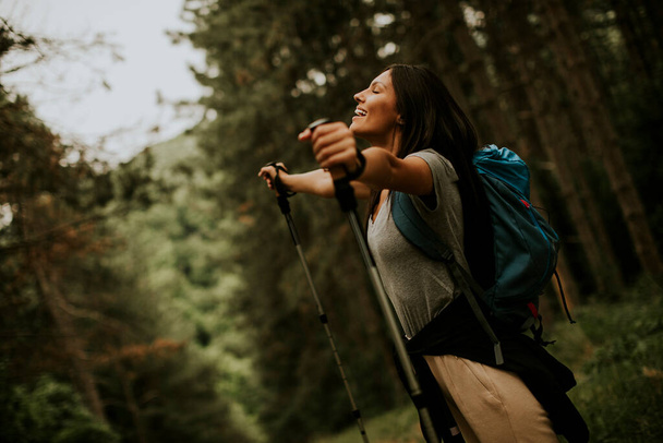 Pretty young female backpacker woman enjoying green beautiful forest around her - Photo, Image