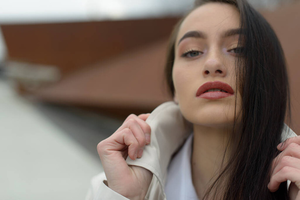 Outdoor portrait of a young beautiful fashionable lady wearing stylish coat . Model looking aside. Female fashion concept. City lifestyle. Close up. - Photo, Image