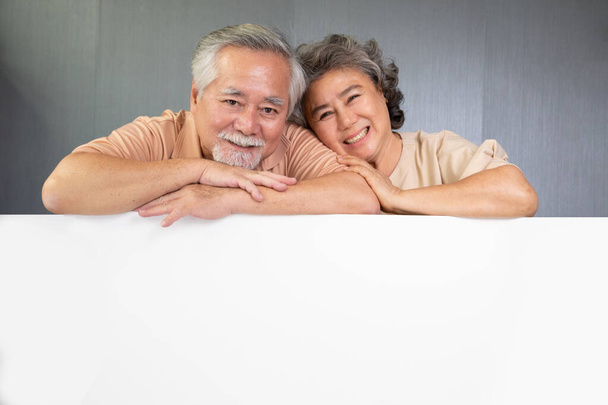 Casal de idosos asiáticos felizes sorrindo e olhando para a câmera no topo da bandeira vazia com espaço de cópia, casal aposentado com um conceito de placa branca - Foto, Imagem