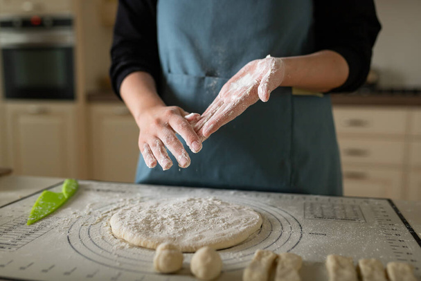 家のパン屋でブルーエプロンで調理で小麦粉で手. - 写真・画像