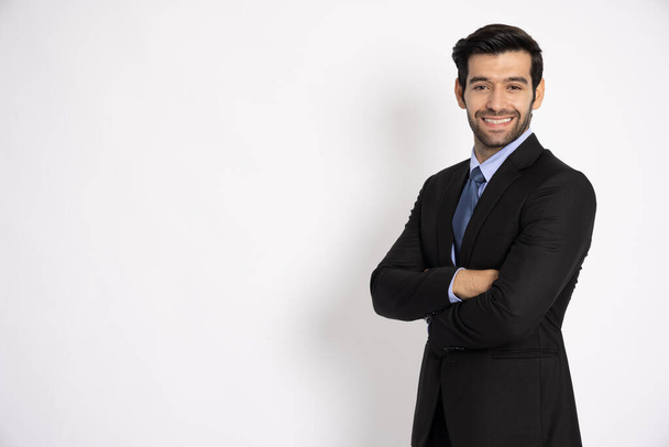 Χαμογελαστή νεαρός επιχειρηματίας με επίσημο μαύρο κοστούμι με τα χέρια σταυρωμένα απομονωμένα σε λευκό φόντο - Φωτογραφία, εικόνα