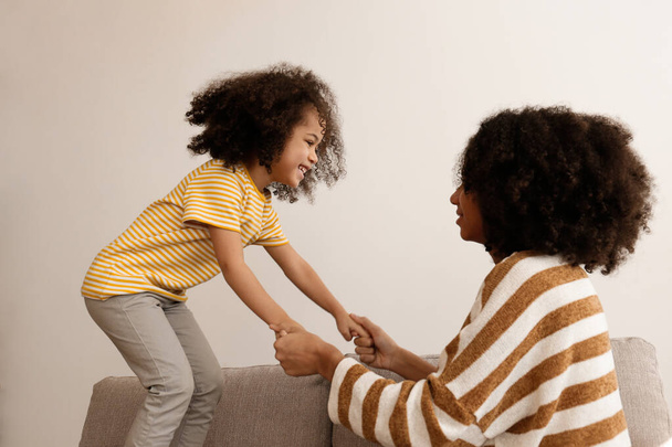 Younger and older sister spending time together at home. Two black girls of different age messing around and playing. Black female siblings having fun and bonding. Background, copy space, close up. - Foto, Imagen